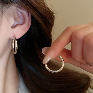 Close-up of minimalist silver hoop earrings worn on ear for a modern elegant look