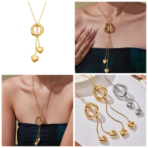 Detail of long heart tassel sweater necklace with geometric ring in gold and silver finish