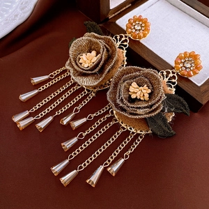 Vue détaillée de boucles d'oreilles rétro avec fleurs brodées et chaînes à pompons
