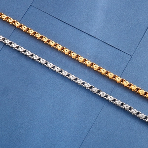 Detailed close-up of gold and silver floral pattern link chains on dark blue surface