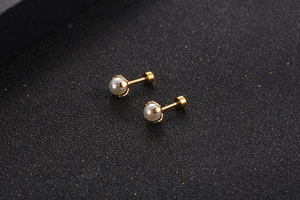 Detailed macro view of gold titanium steel earrings with white pearls and screw backs