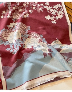 Close-up of red winter scarf featuring blue floral patterns and soft tassel fringes