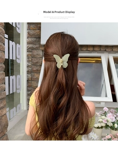 Detail view of a matte mint green butterfly hair claw clip worn on a woman's hair