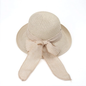 Close-up of beige straw sun hat featuring a large fabric bow and breathable woven texture