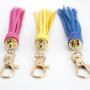 Three colorful leather tassel keychains in pink, yellow, and blue with gold metal hooks