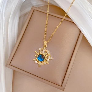 Close-up of gold moon and sun pendant with a dark blue stone on a beige jewelry box