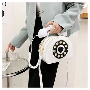 Creative white telephone crossbody bag detail featuring a vintage dial and handset handle