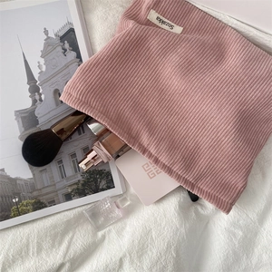 Detail of pink corduroy makeup bag with striped texture on a white fabric background