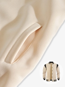 Close-up of beige varsity jacket showing textured fabric and black striped ribbed edges