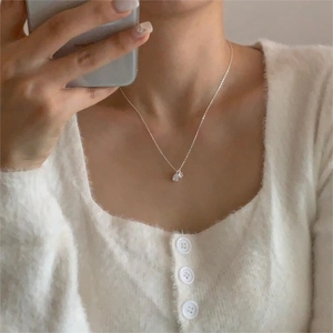 Close-up of minimalist 925 silver necklace with pear-shaped zircon pendant on a model