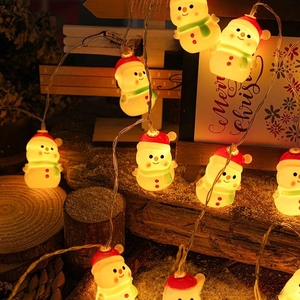 Close-up of warm glowing snowman LED string lights with festive winter props