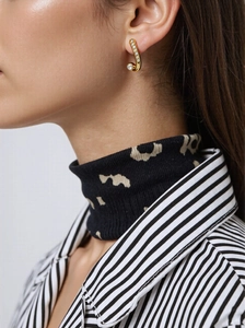 Macro detail of a gold serpent earrings with clear crystals worn by a model