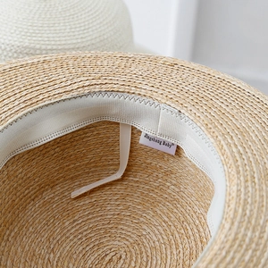 Close-up of woven straw sun hat showing interior sweatband and adjustable drawstring