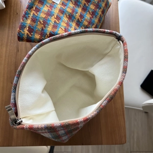 Close-up of checkered wool makeup bag with smooth metal zipper and canvas lining
