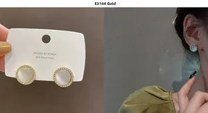 Detail of gold round cat-eye earrings with zircon halo on model and jewelry card