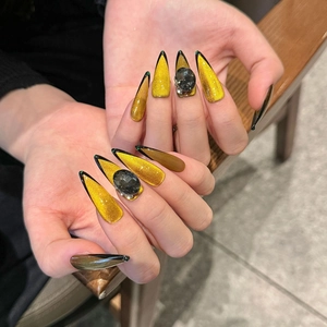 Handmade stiletto press-on nails with golden cat-eye effect and black rhinestone accents