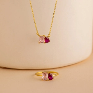 Detailed macro view of a gold ring set with pink and red gemstones on white background