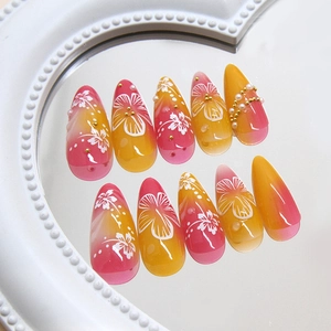 Pink and orange gradient press-on nails with white floral patterns and pearl accents