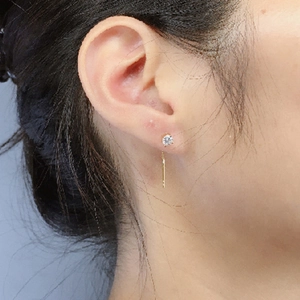 Orecchini a filo d'oro minimalisti con zircone tondo indossati da una modella