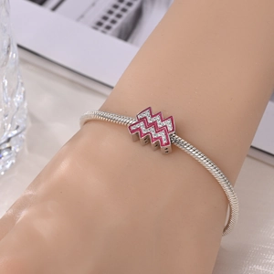 Close-up of silver snake chain bracelet with pink enamel and sparkling rhinestone charm