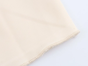 Detailed macro shot of beige fabric texture with precise overlock stitching on the edge