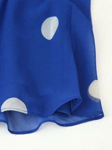 Détail du tissu en mousseline bleue à pois blancs avec coutures fines de l'ourlet