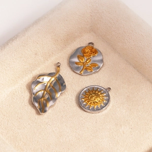Détails macro de trois pendentifs bicolores vintage rose et soleil sur tissu doux