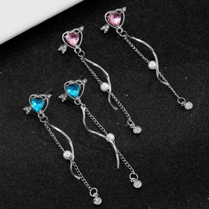 Detail of cupid heart earrings featuring pink and blue gems with long tassel chains