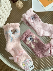 Detailed view of three pairs of pink coral fleece socks with cute cartoon embroidery