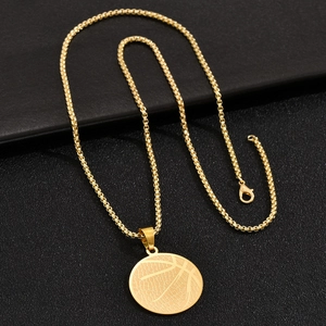 Macro detail of golden basketball pendant necklace featuring textured surface on black background