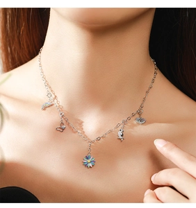 Detail of 925 sterling silver necklace with rainbow bird and daisy charms on a model