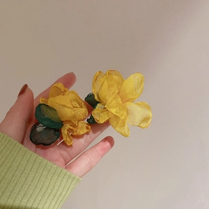 Detail view of handmade yellow fabric flower earrings with green leaf tassels