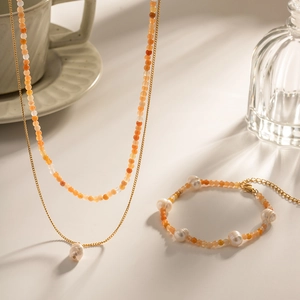 Detail von 18K vergoldetem Set mit Halskette und Armband mit orangefarbenen Perlen