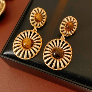 Detail of vintage gold sunburst drop earrings with brown tiger eye stone on black leather