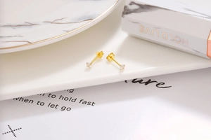 Macro shot of 925 silver gold-plated stud earrings with four-prong set zircons