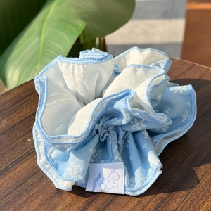 Detail of floral scrunchie in blue and white with Sweet Puppy label on wooden table