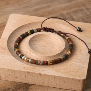 Detail of adjustable woven imperial stone bracelet with colorful beads on wooden tray
