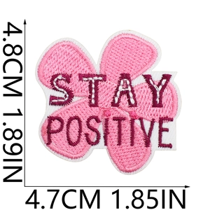 Macro detail of pink flower embroidery patch with Stay Positive text and 4.8cm size