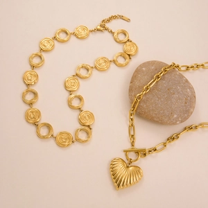 Minimalist 18k gold plated OT toggle necklace with heart pendant on a stone background