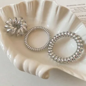 Three-piece set of silver metallic telephone wire hair ties in a shell display