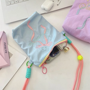 Detail der hellblauen Segeltuchtasche mit Stickerei und rosa Seil-Schultergurt