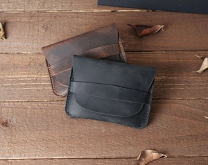 Top view of black and dark brown crazy horse leather card holders on a wood surface