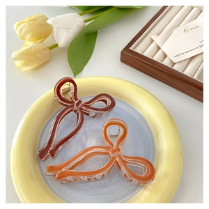 Detail of elegant bow hair clips in amber and brown resin on a decorative tray