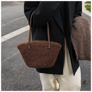 Détail d'un sac cabas en peluche marron foncé avec anses en cuir et perles décoratives