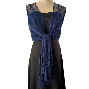 Detail of dark blue lace shawl featuring intricate floral hollow patterns and long tassels