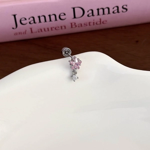 Macro view of pink star zircon stud earring resting on white ceramic plate with a book