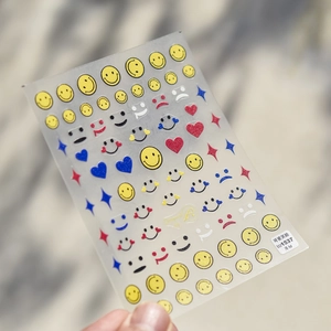 Detailed view of thin embossed smiley face nail stickers with matte finish and gold logo