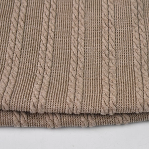 Macro della trama in maglia a trecce marrone e del motivo a coste del berretto