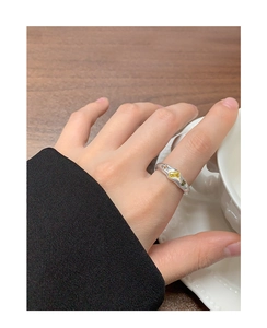 Detailed view of an irregular silver ring with a yellow gem and side stones worn by a hand
