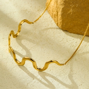 18K gold plated stainless steel wavy pendant necklace with polished box chain on rock